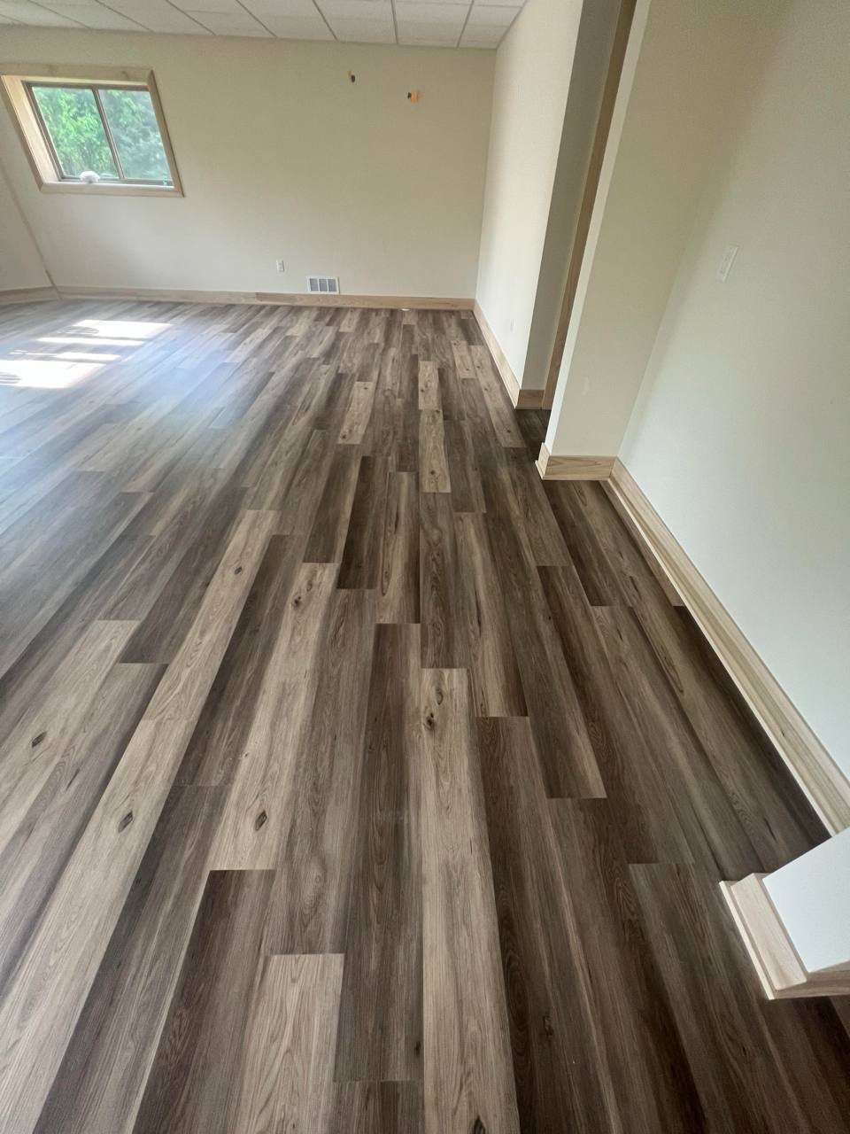Empty room with new gray wood-look luxury vinyl plank flooring