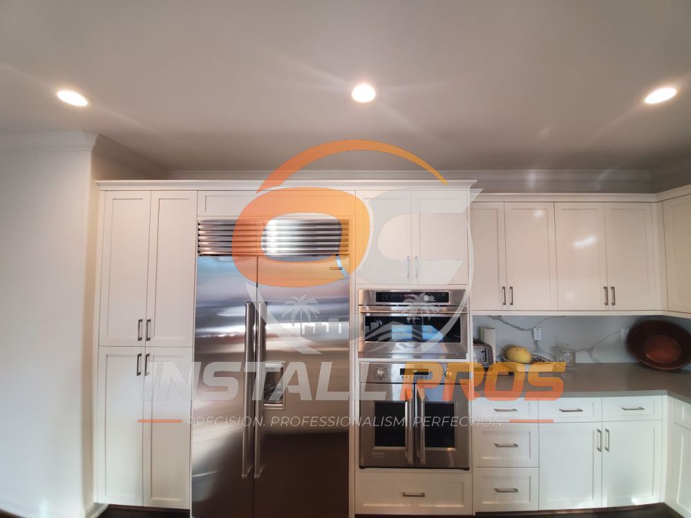 Built-in stainless refrigerator and double wall oven in a white shaker kitchen