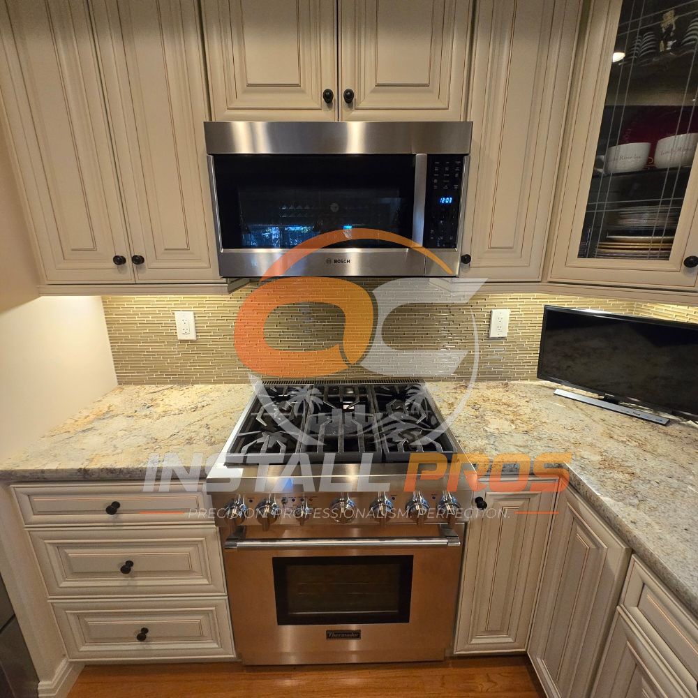Thermador range and Bosch microwave installed in cream cabinets with a mosaic tile backsplash